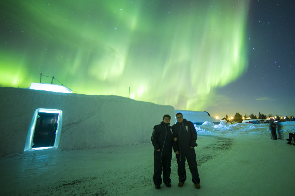Martin & Harriet couple standing infront of the Northern Lights at Ice Hotel