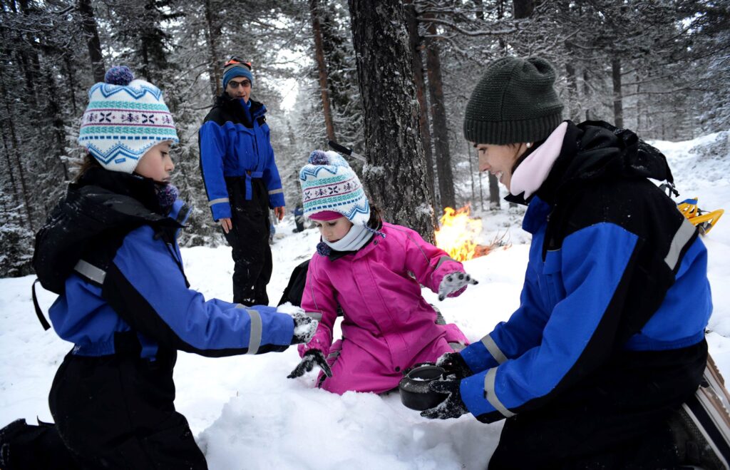 Arctic adventures for families - family playing in snow